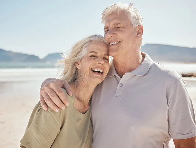 Older couple smiling at the beach