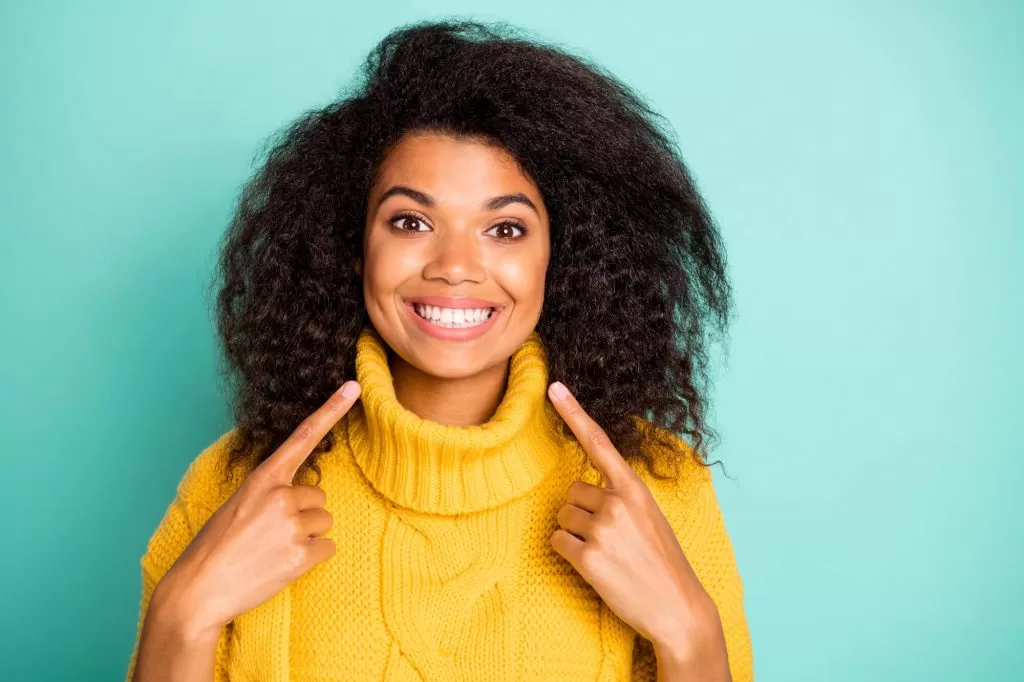 woman wearing yellow sweatshirt smiling at the camera showing off her new porcelain veneers vero beach